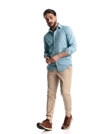 full body picture of attractive casual man looking forward and walking in front of white backgroundの写真素材