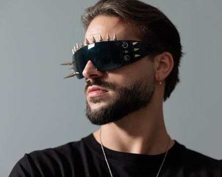 portrait of bearded fashion man with cool sunglasses looking to side and posing in a cool way on grey backgroundの写真素材