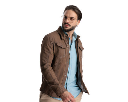 cool casual man in brown jacket with glasses looking away and posing in front of white backgroundの写真素材