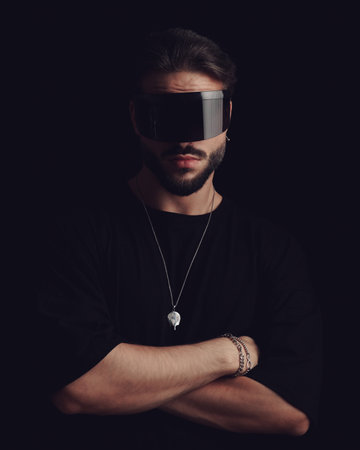 dramatic cool with glasses folding arms and looking forward in front of black backgroundの写真素材