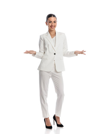 proud elegant businesswoman in white suit being happy, smiling, opening arms and showing in front of white backgroundの写真素材