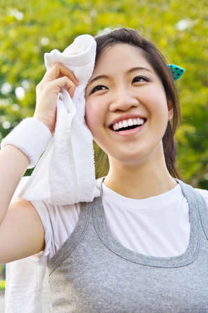Asian woman wiping sweat with a towel after exercisingの写真素材