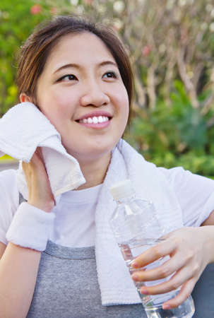Asian woman wiping sweat with a towel after exercisingの写真素材
