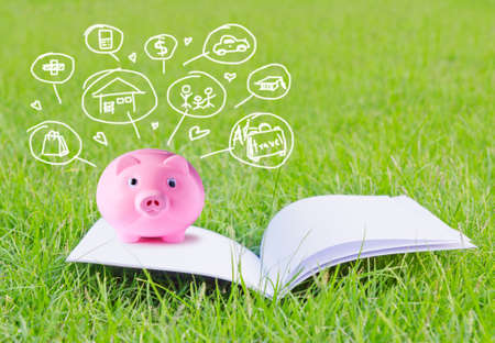 Pink piggy bank on booklet and icon design to represent the concept of saving money の写真素材
