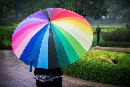 Young woman with multicolor umbrella in rainy dayの写真素材
