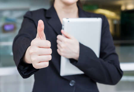 Businesswoman with thumb up and holding digital tabletの写真素材