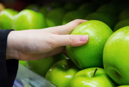 Business woman is choosing apples in the supermarketの写真素材