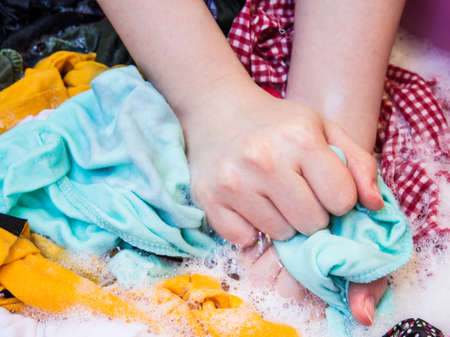 Women washing clothes in the enameled bowlの写真素材
