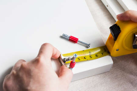 Young woman measuring home furniture with measure tapeの写真素材