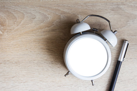 Alarm clock with copy space and pen on wood backgroundの写真素材