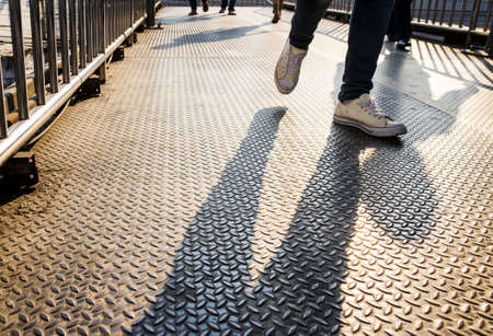 Shadows of people walking on the steel overpassの写真素材