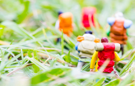 Miniature backpackers walking on the grass