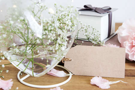 Blank paper tag with gypsophila flowers in heart bottle on wooden backgroundの写真素材