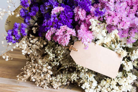 Bouquet of dried flowers with blank paper tag on the wooden tableの写真素材
