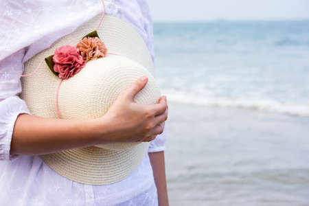 Woman holding hat on the beachの写真素材