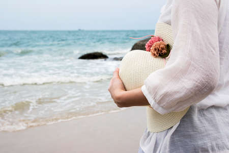 Woman holding hat on the beachの写真素材