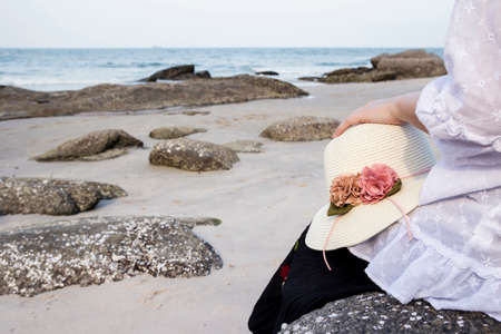 Young woman sitting on stone at beachの写真素材