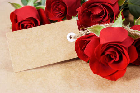 Red roses with blank paper tag on brown paperの写真素材