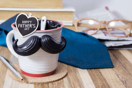 Cup with mustache on wooden table for fathers day conceptの写真素材
