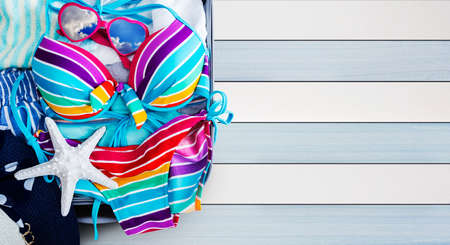 Colorful bikini and clothes in luggage on the wooden backgroundの写真素材