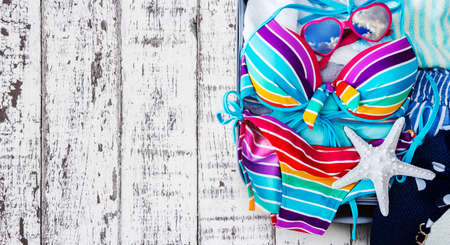 Colorful bikini and clothes in luggage on the wooden backgroundの写真素材