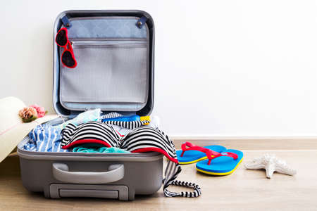 Bikini and clothes in luggage on the laminate floorの写真素材