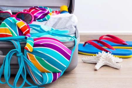 Colorful bikini and clothes in luggage on the laminate floorの写真素材