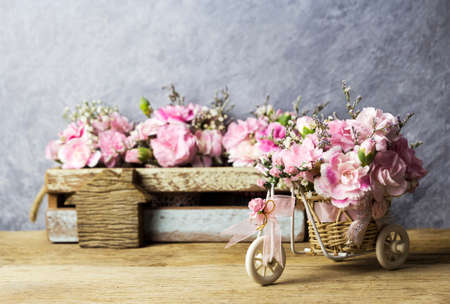 Pink carnation in basket bicycle on old woodの写真素材
