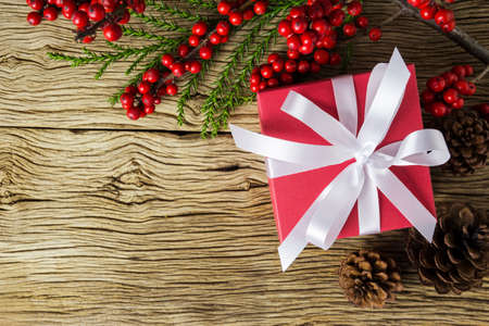Christmas decoration of red gift box and red winterberry on old woodの写真素材