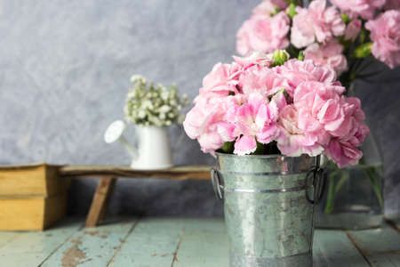Pink carnation flowers in zinc bucket on table woodの写真素材