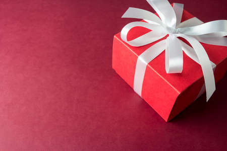 Red gift box with white ribbon on paper backgroundの写真素材