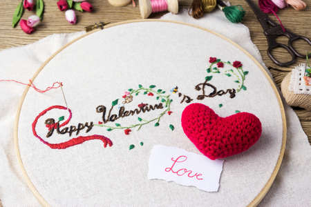 Valentine embroidery with love message and red heart on wood tableの写真素材