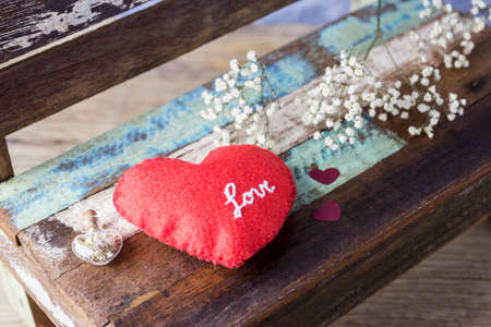 Love concept of red felt heart and gypsophila flowers on vintage chair for valentines day and weddingの写真素材