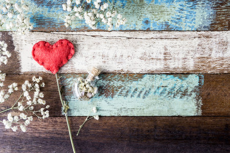 Love concept of red felt heart and gypsophila flowers on vintage chair for valentines day and...