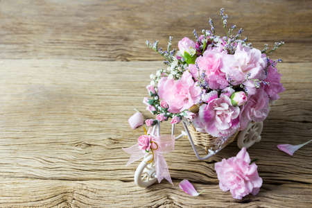 Pink carnation in bicycle basket on old woodの写真素材