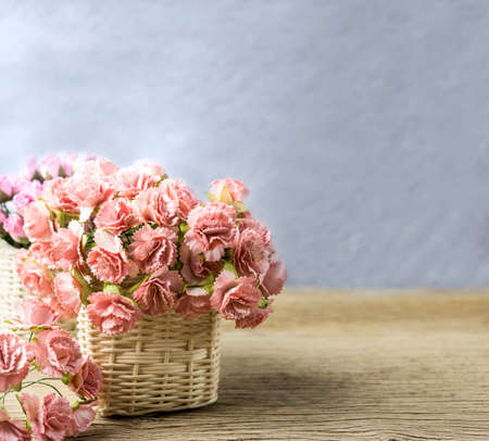 Paper carnation and rose flowers in basket on old wood with copy spaceの写真素材