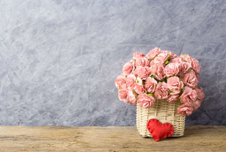 Pink paper carnation in weave basket on old wood with copy space の写真素材