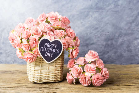 Happy mothers day concept of Paper carnation in weave basket on old wood with copy space の写真素材