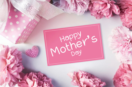 Happy mothers day message on pink paper and carnation flowers and gift boxの写真素材