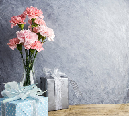 Mothers day concept of pink carnation flowers in clear bottle and gift box の写真素材