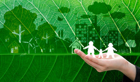 Ecology concept design of business woman hand holding white paper family symbol on fresh green leaf texture backgroundの写真素材