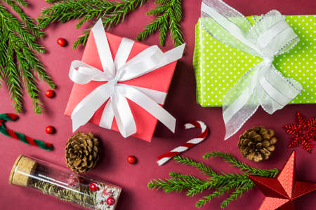 Christmas and New year decoration of gift box and pine leaves and pine cone on paper red backgroundの写真素材