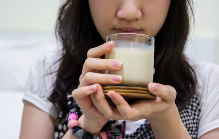 Young woman drinking soybean milk in the bedroomの写真素材