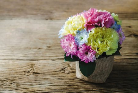Carnation and Chrysanthemum flowers in pot on old wood at home