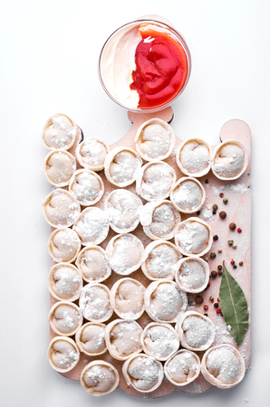 Raw dumplings on a wooden board. Seasoning, bay leaf, pepper, ketchup, studio lightingの写真素材