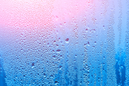 Window with condensate or steam after heavy rain, large texture or background with glare of lightの写真素材