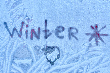Frozen background with an inscription winter and a pattern on the window glassの写真素材