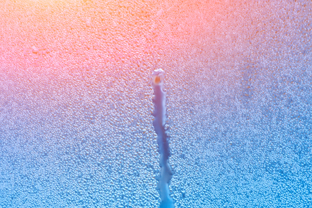 Window with condensate or steam after heavy rain, large texture or background with glare of lightの写真素材