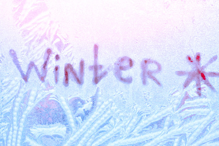 Snow texture with the inscription "winter" on the frozen windowの写真素材