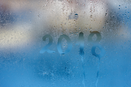 Hand draw numbers of the year and drops of water on the glass. Condensation and raindrops on the window, shallow depth of fieldの写真素材